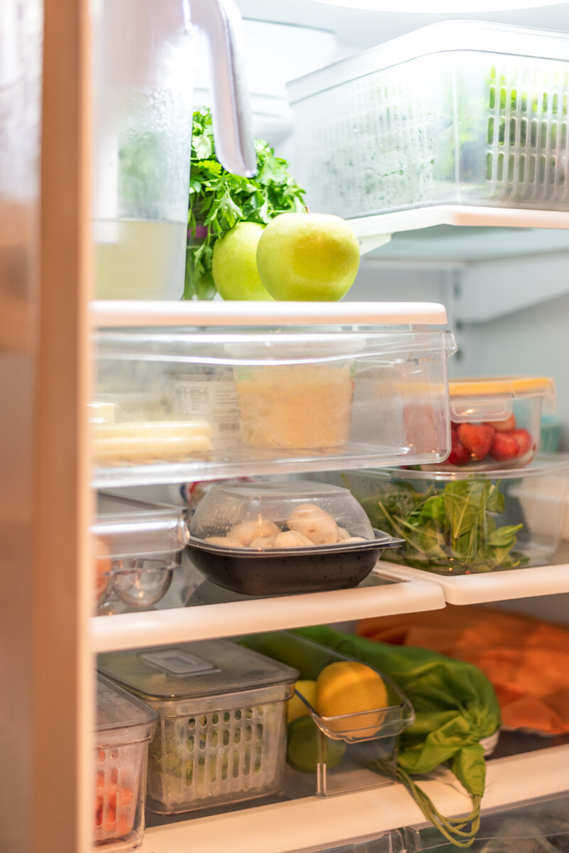 Open refrigerator with fresh produce and food containers.
