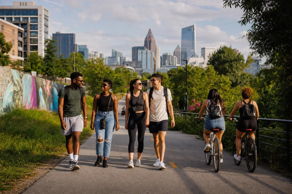 Friends walking and biking the Atlanta BeltLine with the Midtown skyline behind them