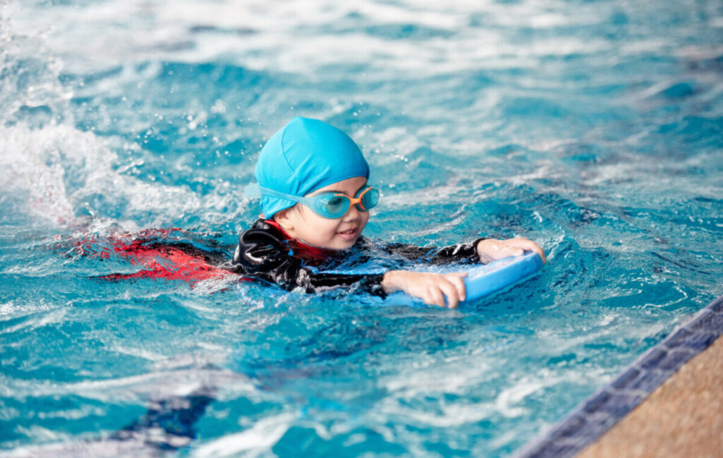 Young child practicing swimming with an instructor