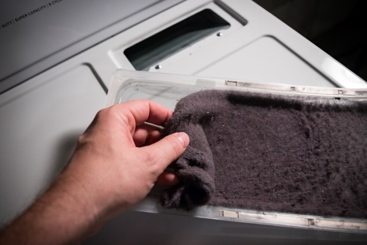 Hand removing accumulated lint from a clothes dryer filter