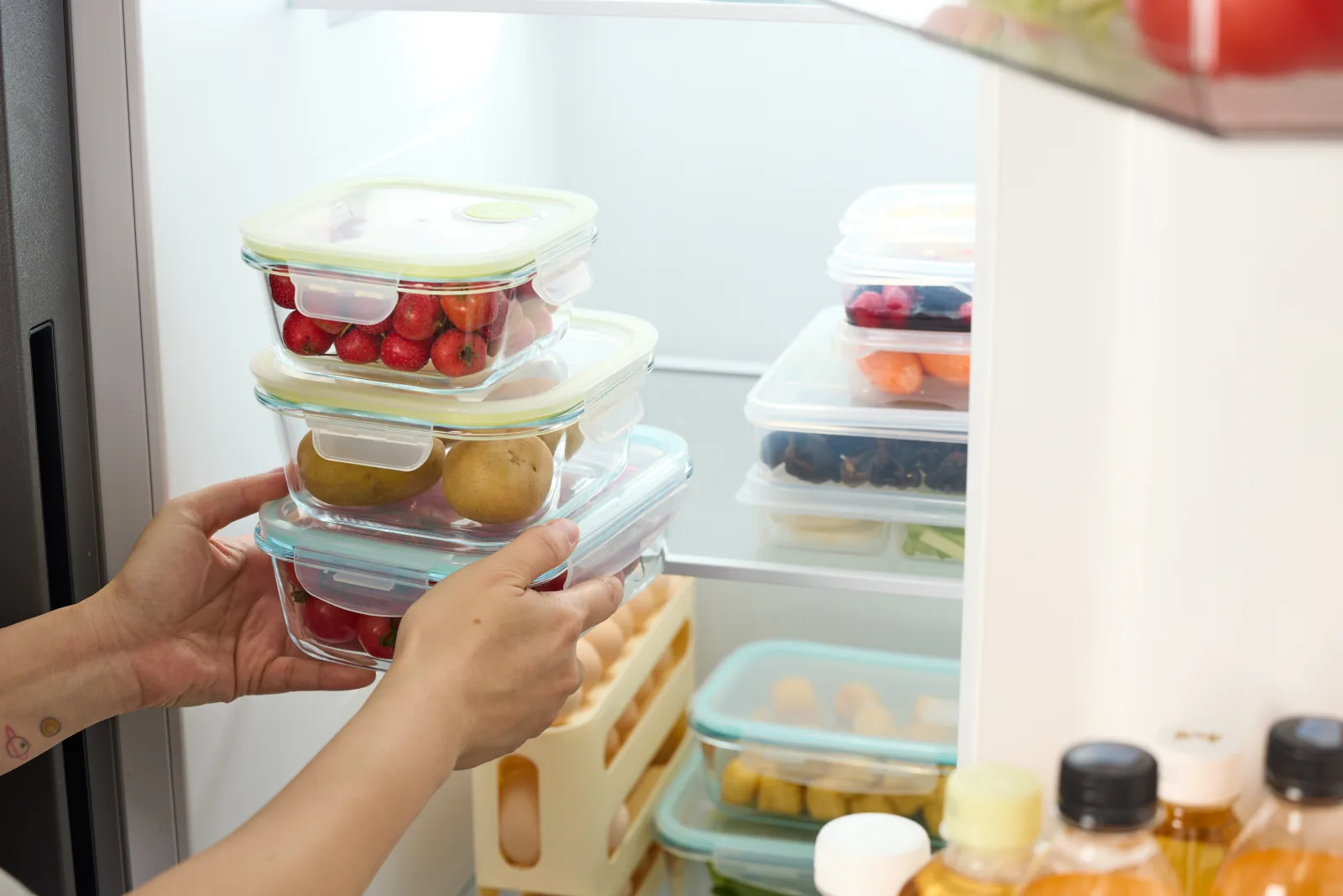Fresh fruit stored in clear containers inside an organized refrigerator.